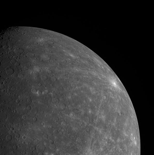The scarred surface of Mercury, revealed in detail by Messenger. A large pale crater at the horizon stretches long rays across the surface.